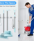 Broom And Mop Holder Wall Mount Organizer With Five Racks And Four Hooks, Heavy Duty Stainless Steel used in a home setting with mop and bucket.