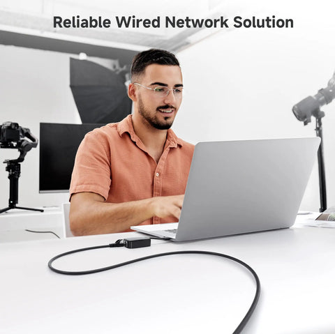 Man using laptop with 10Gbps Snagless Cat6 Ethernet Cable 25ft Slim Profile Patch Cord for reliable wired connection in office