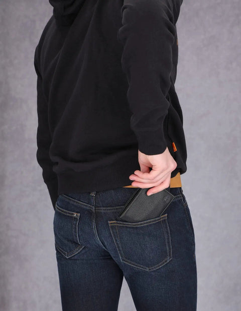 Person placing RFID Blocking Leather Wallet For Men With Removable ID Holder And Slim Design into back pocket