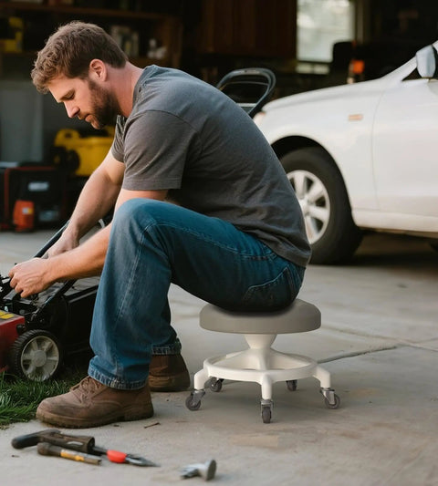 Man using Low Profile Rolling Stool With 360 Degree Rubber Wheels, Heavy Duty 450 Lb Capacity, PU Seat, Steel Connector And Anti Tip Base, Easy Assembly For Garage, Workshop And Mechanic Tasks, Gray while working on lawn mower