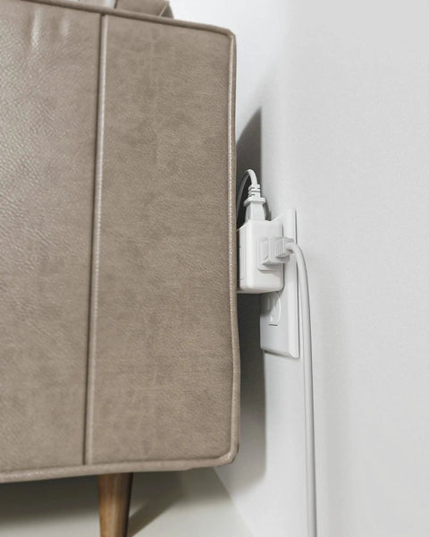 Five Way Wall Outlet Extender With 90 Degree Angled Side Plugs behind sofa, ultra slim flat 3 prong wall adapter in use.