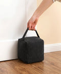 Heavy Duty Weighted Door Stopper With 4.4 Lb Internal Weight with handle, soft fabric, placed under white door on wood floor.