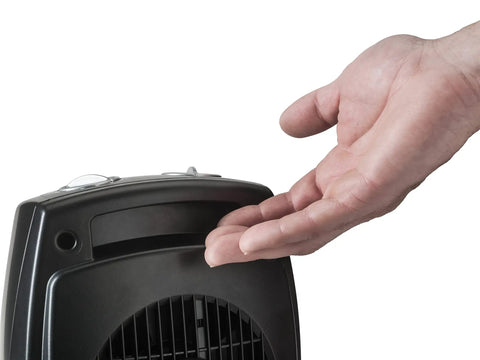 Hand feeling heat from Compact Ceramic Space Heater CD09250 With Adjustable Thermostat For Tabletop Or Under Desk Use.