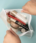 Person holding Leakproof Clear Toiletry Bags Set Of 4, TSA Approved Quart Size Zipper Bags And Large Pouches, BPA Free, filled with cosmetics