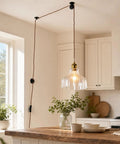 Fang Yan Mei Plug in Pendant Light with clear fluted glass shade hanging over a wooden kitchen island, featuring a plug in cord.