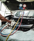 Mechanic using gauge tools for air compressor check under car hood