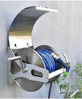 Top Shelf Stainless Steel Garden Hose Reel Cart With Quick Draw Wall Mount Holds Forty Meters Of Half Inch Irrigation Tubing mounted on a wall.