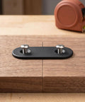Close-up of 30 Pcs Black Stainless Steel Straight Flat Brackets Mending Plates 2.36 By 0.63 Inches with screws on wood surface