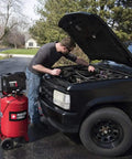 Man using Rock Solid 20 Gallon Portable Air Compressor With Oil Free Twin V Cast Iron Pump for automotive repairs.