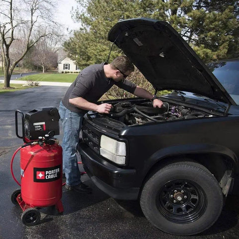 Man using Rock Solid 20 Gallon Portable Air Compressor With Oil Free Twin V Cast Iron Pump for automotive repairs.