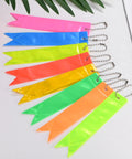 8 Pack Reflective Safety Pendants With Chains For Backpacks, Running And Cycling, in fluorescent colors arranged on a table.