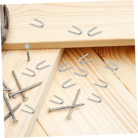 50 Pack U Shaped Fence Staples For Quick Install And Strong Hold Durable Metal Garden Stakes For Fences Landscaping And DIY Projects Multi Function Iron Pegs scattered on wooden surface