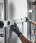 Person using LYIYEYAN 24-Inch Magnetic Torpedo Spirit Level, Heavy Duty Ruler for Carpen on drywall with gloves.