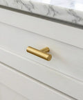 Premium Brushed Brass Cabinet Knobs 2 Inch Dresser Pulls Hardware Set 12 Pack on a white drawer with a marble countertop.