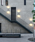 Modern building facade with 2 Pack Outdoor Wall Sconce Lights With Up And Down LED Cylinder Design, 304 Stainless Steel Waterproof Exterior Porch Lighting.