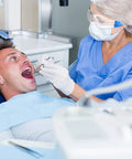 Dentist wearing 48 Pack Safety Glasses With Clear Lenses For Work And Lab Eye Protection Goggles examining a patient's mouth