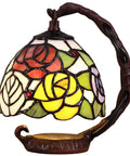 Colorful stained glass lampshade of Rose Tiffany Style Stained Glass Table Lamp With Six Inch Lampshade On Sturdy Cast Iron Base Pink Handmade Decor That Pops For Living Room Or Bedroom LED Bulb Included 25W Max E12 Compatible on ornate iron stand.