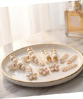 Eight Piece Pearl Waist Tightener Pin Set Elegant Alloy Dress Cincher Clips on a decorative plate with a soft background.