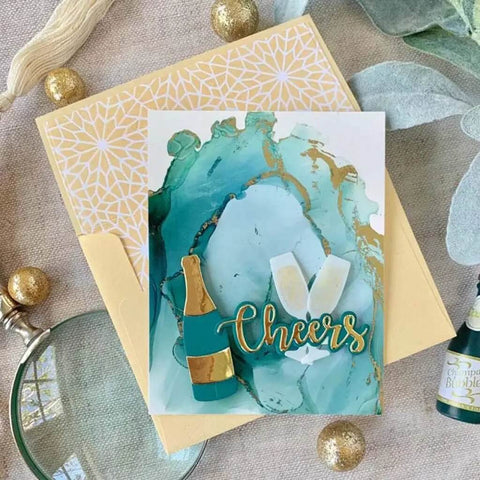 Handmade card with wine glasses and 'Cheers' on a decorative background with gold and blue accents.