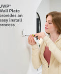 Woman installing Smart WiFi Thermostat With Conventional And Heat Pump Compatibility, X2S Gray on wall using UWP Wall Plate