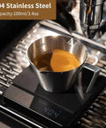 3.4 Oz Espresso Cup With Handle Premium Stainless Steel Cappuccino Accessories Double Spout Measuring Cup With Dual Scale Latte Shot Mug With V Shaped Mouth 100 Ml filled with espresso on scale