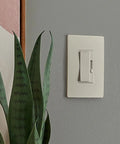 Heavy Duty 150 Watt Led Dimmer Switch 3 Way Rocker Control Brightness Adjustment For Dimmable Bulbs Smooth Flicker Free Operation Built To Last Easy Hookup Almond Finish mounted on a wall with plant.