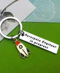 Funny Aerospace Engineer Keychain Gift For Graduation And Appreciation with rocket charm on green background