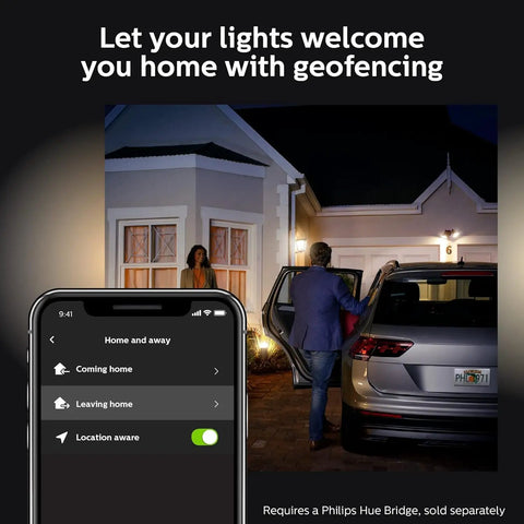 Hue Lucca White Outdoor Wall Light With Dusk To Dawn Sensor lighting up driveway as couple approaches home at night