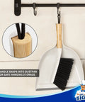 Portable Dustpan and Brush Set With Bamboo Handle in White hanging on a hook; close-up of bamboo handle loop.