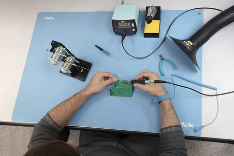 Person using ESD Soldering Mat Blue 600mm By 900mm Pro Grade Large Work Surface With Two 10mm Press Stud Connectors for electronics work.