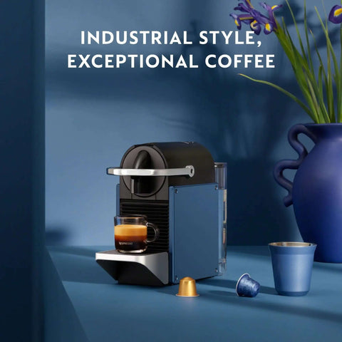 Pixie Espresso Machine By DeLonghi In Dark Blue on counter with espresso cup and capsules