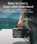 Person holding 600W Portable Power Station With 288Wh LiFePO4 Battery Backup, Solar Generator, on a dock with mountain view.