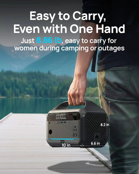 Person holding 600W Portable Power Station With 288Wh LiFePO4 Battery Backup, Solar Generator, on a dock with mountain view.