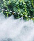 50 Pack Adjustable Brass Misting Nozzles With Atomizing Spray Emitters For Your Garden Greenhouse Patio Misting And Outdoor Cooling System Drip Irrigation Sprinkler Heads spraying fine mist in greenery background