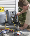 Man using HVAC gauges connected to AC unit for maintenance check outside a building