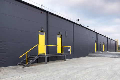 Outdoor LED Wall Pack Light With Dusk To Dawn Photocell, 5000K Daylight, 120-277V, installed on warehouse exterior, dark bronze finish