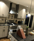 Modern kitchen with white cabinets, stainless steel appliances, and island. Lighting features pendant lamps.