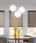 Dining room with 10 Inch Mid Century Modern Globe Pendant Light With Frosted Glass Orb, White Finish, over round table and chairs