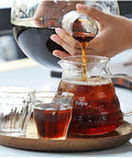 Pouring brewed coffee from a glass carafe into a glass pitcher, featuring Big Batch Cold Brew Drip Tower, 2500Ml Large Iced Coffee Maker.