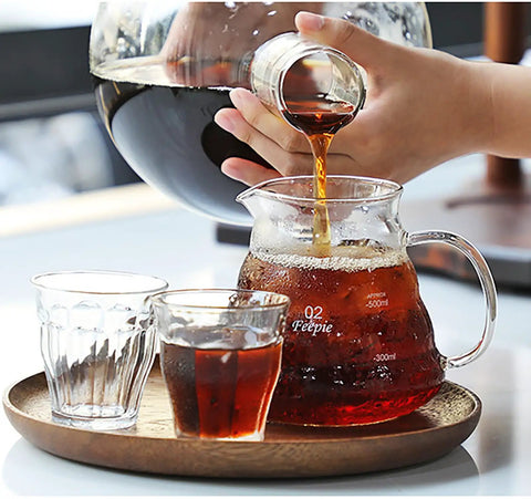 Pouring brewed coffee from a glass carafe into a glass pitcher, featuring Big Batch Cold Brew Drip Tower, 2500Ml Large Iced Coffee Maker.