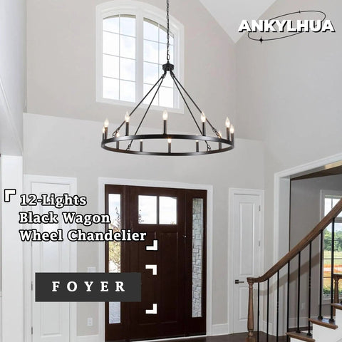 12-Light black wagon wheel chandelier in farmhouse foyer setting with high ceiling and windows.