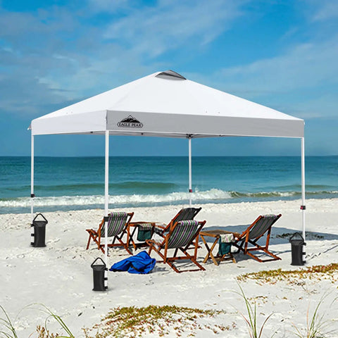 10x10 Foot Pop Up Canopy Tent With Wheeled Carry Bag set up on beach, easy one person setup, includes weight bags, white color.