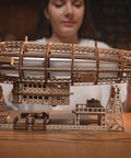 Person assembling Luminous Zeppelin LED 3D Wooden Puzzle Kit For Adults with detailed airship model on table