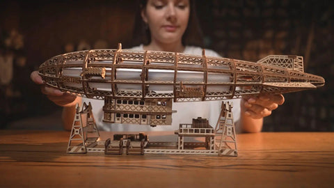 Person assembling Luminous Zeppelin LED 3D Wooden Puzzle Kit For Adults with detailed airship model on table