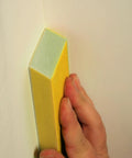 Hand using Very Fine 220 Grit Dual Angle Sanding Sponge 3 By 5 By 1 Inches for tight corner on wall