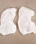 Straight Up Clean And No Drama Disposable Nonwoven Hair Covers With Tension Free Elastic Bands For Salon Beauty Chef Jobs And Long Daily Grind Sessions Pack Of 20 Fresh Caps, two white nonwoven hair covers on fabric.