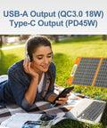 Woman using portable solar generator with 60 watt panel and 230 Wh LifePo4 battery for charging devices outdoors.