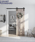 Sliding Barn Door Hardware Kit With Soft Close For 5 To 10 Ft Doors installed on wooden door in living room