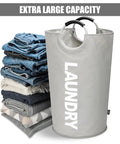 115L XXL Collapsible Laundry Hamper With Aluminum Soft Grip Handle, grey freestanding basket with stacked clothes nearby.