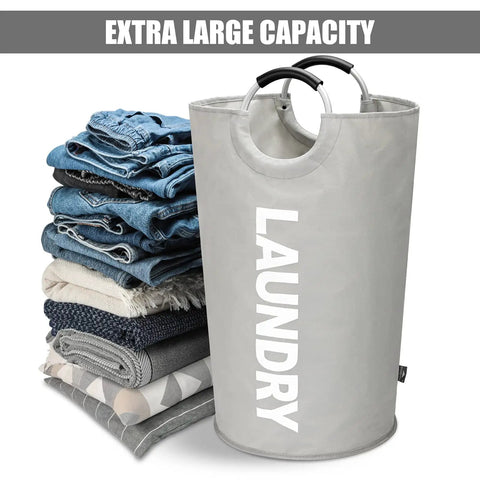 115L XXL Collapsible Laundry Hamper With Aluminum Soft Grip Handle, grey freestanding basket with stacked clothes nearby.